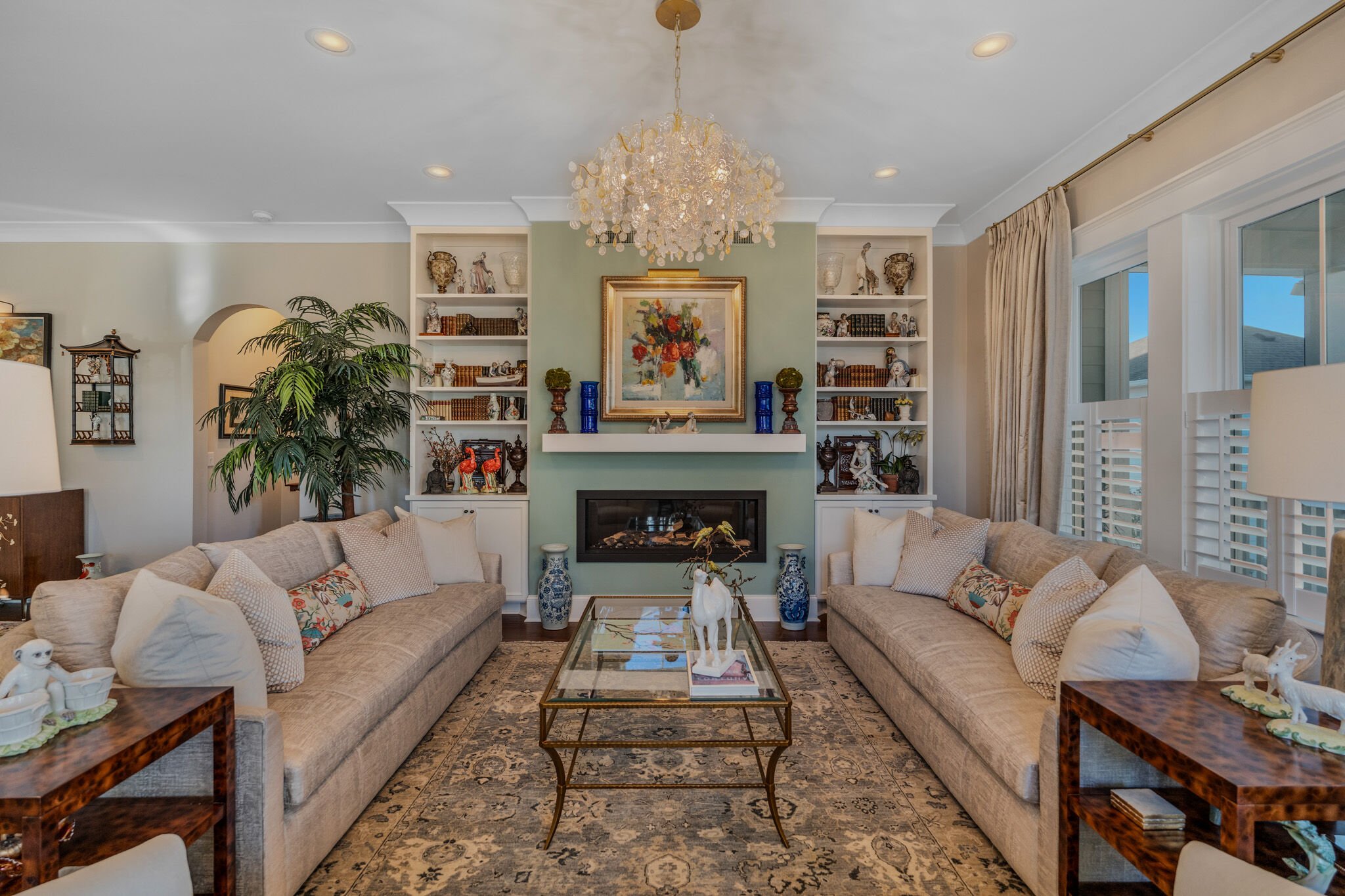 Living room with linear gas fireplace, built-in bookshelves and chandelier