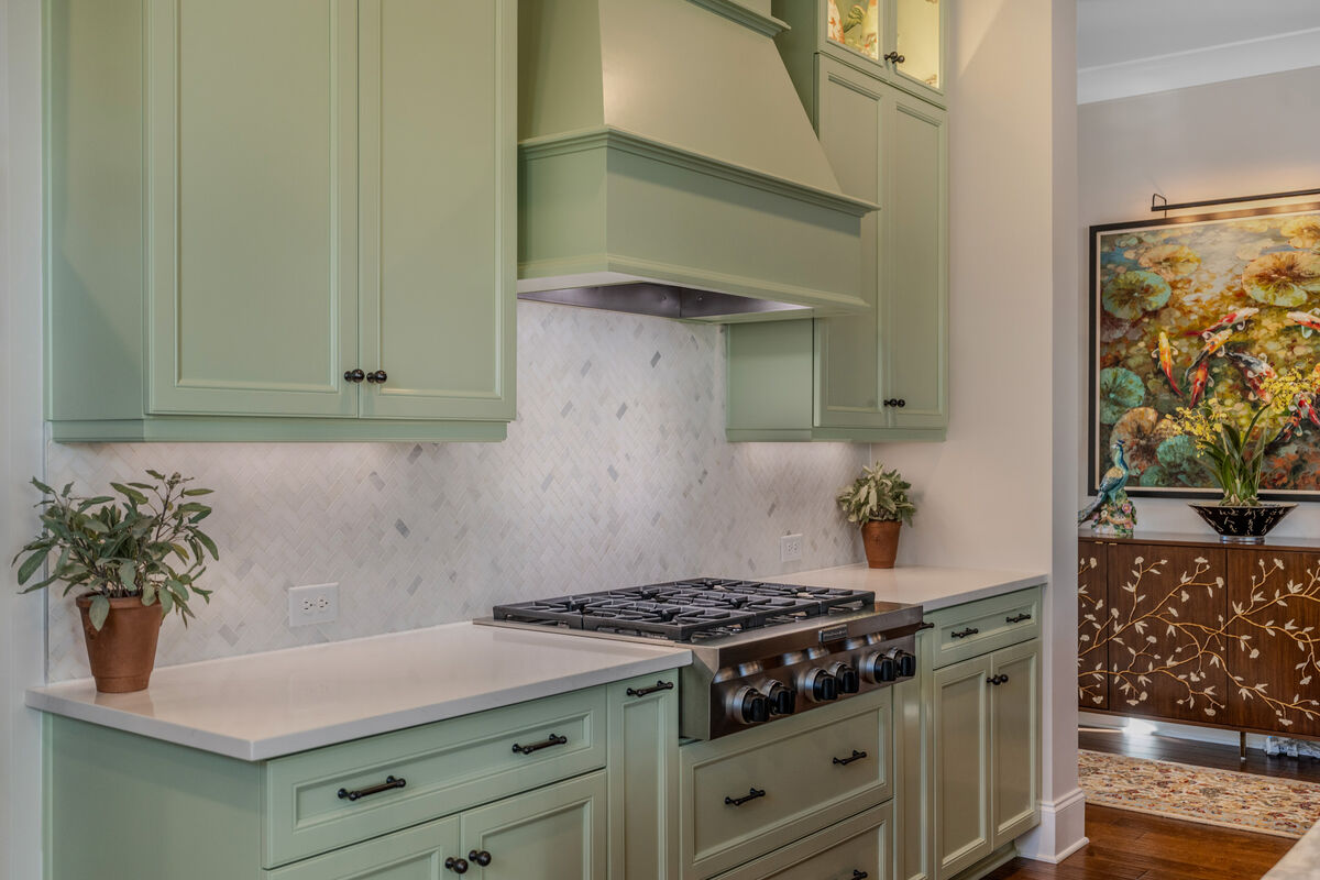 Gas rangetop under a sage range hood
